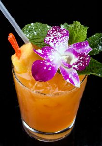 The famous Mai-Kai Mai-Tai rum drink served in a tumbler and decorated with a pineapple stick, orchid bloom and powered sugar.