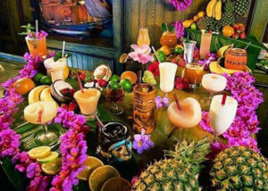 Displaying a delightful spread of colorful Polynesian tropical drinks decorated with leis and tropical fruits.