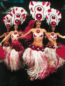 Four female Polynesian dancers in beautiful head dresses and red and white costumes.