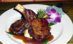 Succulent Pork chops served over mashed potatoes with orchid bloom.