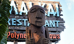 Authentic hand crafted wooden tiki sculpture offset by the signature wooden Mai-Kai sign and blue sky.